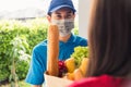 Delivery man wear protective face mask making grocery giving fresh food to woman customer Royalty Free Stock Photo