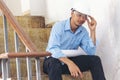 Asian young engineer man stress and failure in architecture project sitting at office on construction site. Upset despair civil Royalty Free Stock Photo