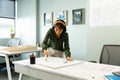 Asian young female architect drawing blueprint at table in creative office Royalty Free Stock Photo