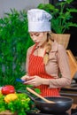 Asian young female chef housewife wears white tall cook hat and apron standing smiling on smartphone call holding wooden spoon Royalty Free Stock Photo