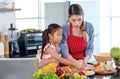 Asian young female chef mother wears apron teaching little cute girl daughter cooking preparing making delicious sandwiches with