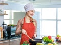 Asian young female chef wears white tall cook hat and apron smiling posing ready to cooking food with pan at counter with bread Royalty Free Stock Photo