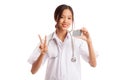 Asian young female doctor show victory sign with blank card