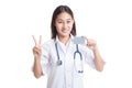 Asian young female doctor show victory sign with blank card.