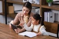 Asian young female housewife mother tutor teacher sitting smiling on table in living room holding tablet computer pointing Royalty Free Stock Photo