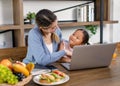 Asian young female mother and little cute girl daughter sitting smiling learning studying doing homework online via laptop Royalty Free Stock Photo