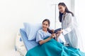 Asian young female patients lying in the bed are looking at the results of modern methods of treatment via tablet tools, with