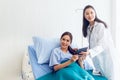 Asian young female patients lying in the bed are looking at the results of modern methods of treatment via tablet tools, with
