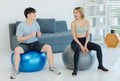 Asian young fit male female husband wife in sportswear sport bra leggings sneakers sitting on exercise ball talking smiling Royalty Free Stock Photo