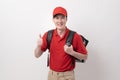 Asian Young food delivery man wearing red uniform carrying food baggage smiling on white background Royalty Free Stock Photo