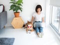 Asian young freelance girl productive work at home lifestyle while using computer device with smart handsome dog pet lie down on