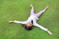 Asian young girl child lying on green lawn at the garden. Kid lies on grass Royalty Free Stock Photo