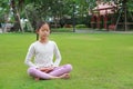 Asian young girl child practicing mindfulness meditation sitting on lawn in the garden. Peaceful concept Royalty Free Stock Photo