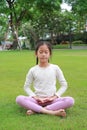 Asian young girl child practicing mindfulness meditation sitting on lawn in the garden. Peaceful concept Royalty Free Stock Photo