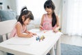 Asian young girl children drawing and coloring paper in living room. Little adorable sibling child sister sit on table, learn how