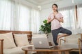 Asian young girl doing Yoga, follow online trainer in laptop at home. Active Beautiful sportswoman doing lockdown activity in