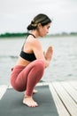 Asian young girl doing yoga outdoors on the pier by the lake Royalty Free Stock Photo