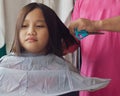 Asian young girl is getting haircut at home from the father. Young teenage girl