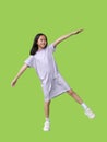 Asian young girl kid standing on one leg for balance and arms outstretched or keeping arms raised isolated on green background. Royalty Free Stock Photo