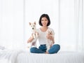 Asian young girl smile with hold Japanese white Shiba Inu adorable dog and puppy Maltese in her hand on bed after they are playing Royalty Free Stock Photo