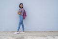 Asian young girl wear jean and color ful shirt  hold book standing with blue background Royalty Free Stock Photo