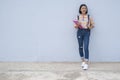 Asian young girl wear jean and color ful shirt  hold book standing with blue background Royalty Free Stock Photo