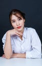 Asian young glamour trendy urban fashionable female model wearing makeup in a casual white shirt sitting smiling on black backgrou Royalty Free Stock Photo