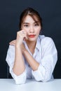 Asian young glamour trendy urban fashionable female model wearing makeup in a casual white shirt sitting smiling on black backgrou Royalty Free Stock Photo
