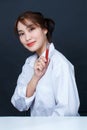 Asian young glamour trendy urban fashionable female model wearing makeup in casual white shirt sitting smiling holding red lipstic Royalty Free Stock Photo