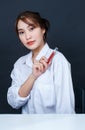 Asian young glamour trendy urban fashionable female model wearing makeup in casual white shirt sitting smiling holding red lipstic Royalty Free Stock Photo