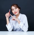 Asian young glamour trendy urban fashionable female model wearing makeup in casual white shirt sitting smiling holding red lipstic Royalty Free Stock Photo