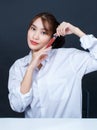 Asian young glamour trendy urban fashionable female model wearing makeup in casual white shirt sitting smiling holding red lipstic Royalty Free Stock Photo