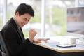 Asian young handsome black short hair happy successful male businessman worker in formal suit sit smile  and raise fitch punch Royalty Free Stock Photo