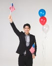Asian young and handsome business man wearing dark suit standing on white background with red,white, blue balloon holding American Royalty Free Stock Photo