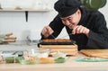 Asian young handsome chef man, in black uniform, smiling while cooking japanese food called takoyaki in hot pan with ingredients Royalty Free Stock Photo