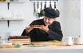 Asian young handsome chef man, in black uniform, smiling while looking at japanese food called takoyaki in plate at kitchen Royalty Free Stock Photo