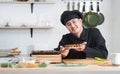 Asian young handsome chef man, in black uniform, smiling while showing japanese food called takoyaki in plate at kitchen Royalty Free Stock Photo