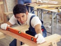 Asian young  male carpenter using Water Level Gauge Ruler in the room with wood work Royalty Free Stock Photo