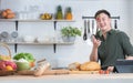 Asian young handsome man smiling enjoy cooking in modern kitchen, having fun tossing strawberry in the air, using tablet while Royalty Free Stock Photo