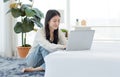 Asian young happy cheerful female model sitting smiling on fluffy carpet floor using browsing surfing internet shopping online Royalty Free Stock Photo