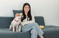 Asian young happy cheerful female owner sitting smiling on cozy sofa couch holding eating popcorn glass bowl snack watching movie