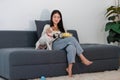 Asian young happy cheerful female owner sitting smiling on cozy sofa couch holding eating popcorn glass bowl snack watching movie