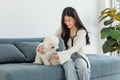 Asian young happy cheerful female owner sitting smiling on cozy sofa couch playing fetching blue ball with best friend small Royalty Free Stock Photo