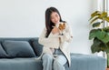 Asian young happy cheerful female owner sitting smiling on cozy sofa couch playing hugging cuddling with best friend small Royalty Free Stock Photo