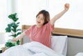 Millennial Asian young happy cheerful lazy sleepy female teenager sitting laying smiling on pillow under thick warm blanket on