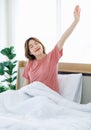 Asian young happy cheerful lazy sleepy female teenager sitting laying smiling on pillow under thick warm blanket on