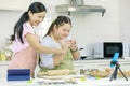 Asian young happy chubby down syndrome autistic daughter wears apron standing smiling laughing in kitchen touching hands with Royalty Free Stock Photo