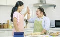 Asian young happy chubby down syndrome autistic daughter wears apron standing smiling laughing in kitchen touching hands with Royalty Free Stock Photo