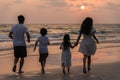 Asian young happy family enjoy vacation on beach in evening. Dad, mom and kid relax running together near sea while silhouette Royalty Free Stock Photo