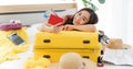 Asian young happy female traveler showing red passport with air tickets leaning on big yellow trolley luggage on bed look at Royalty Free Stock Photo